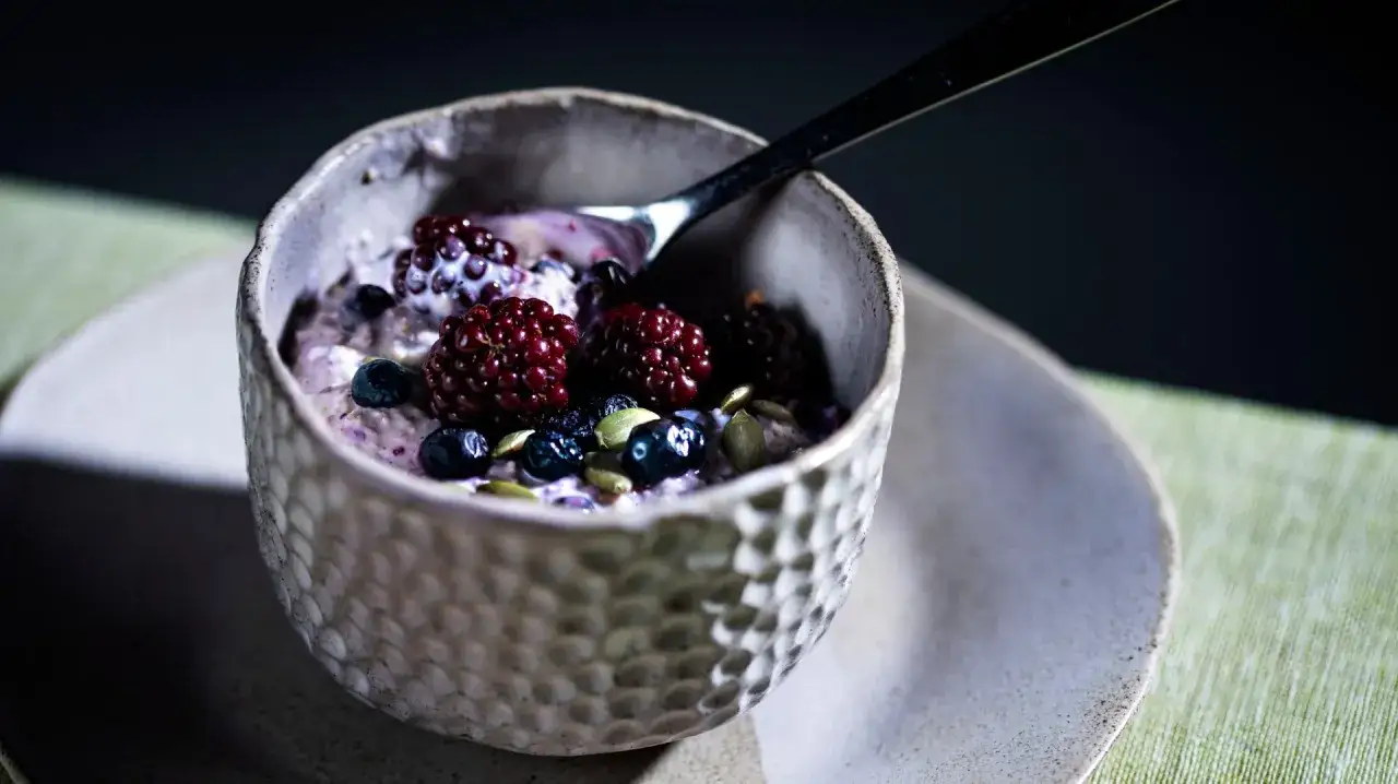 En sk&aring;l med overnight oats toppad med bj&ouml;rnb&auml;r, bl&aring;b&auml;r och pumpafr&ouml;n. Perfekt f&ouml;r en snabb och n&auml;ringsrik frukost.
