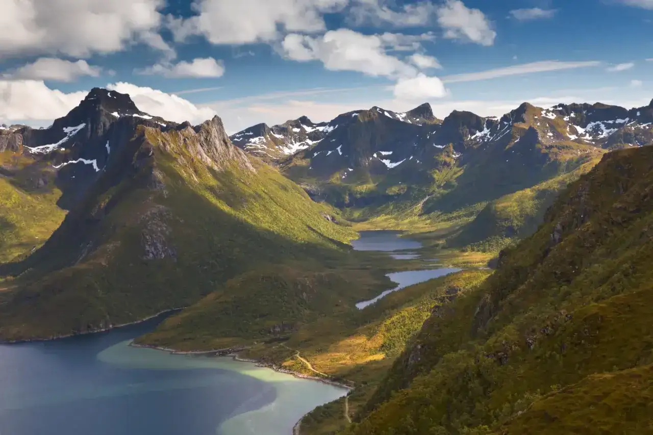 Majestätiska berg med snöklädda toppar och gröna sluttningar ramar in en slingrande sjö. En perfekt plats för en aurlandsdalen vandring.