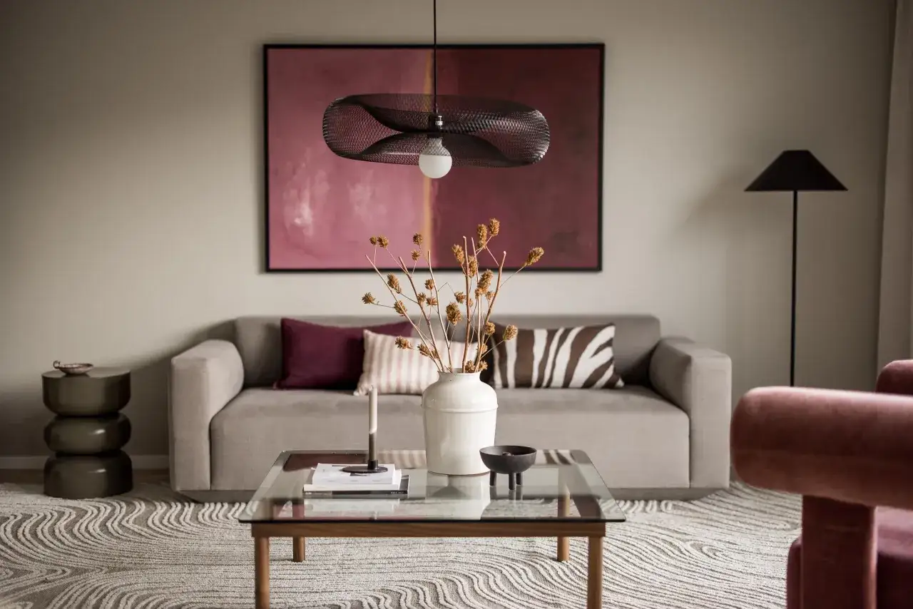 En stilren soffa i vardagsrummet med en abstrakt tavla och en modern lampa. Perfekt soffa vardagsrum inspiration.