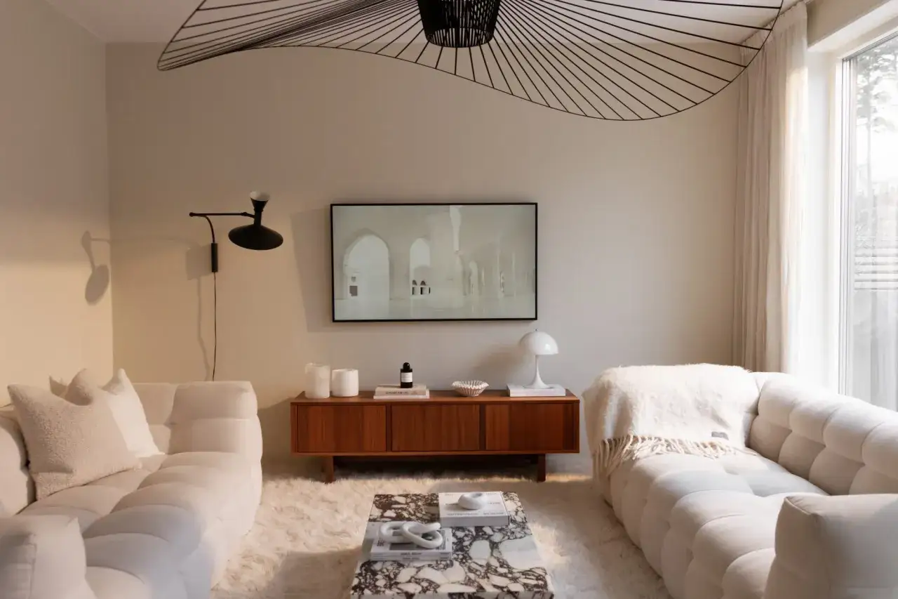Mysigt hotellrum inredning med vita soffor, marmorbord och en stor taklampa.