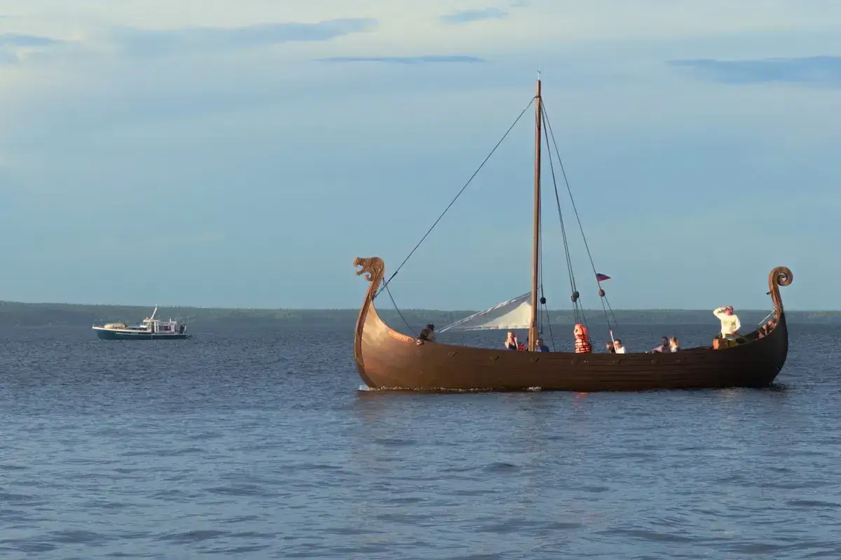 En replika av ett vikingaskepp med passagerare seglar på vattnet. Fascinerande vikingar fakta!