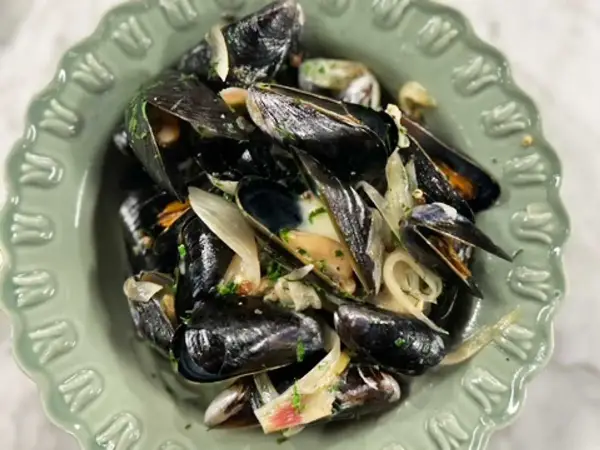 En skål med ångade musslor med lök och persilja. Ett enkelt och gott musslor recept.