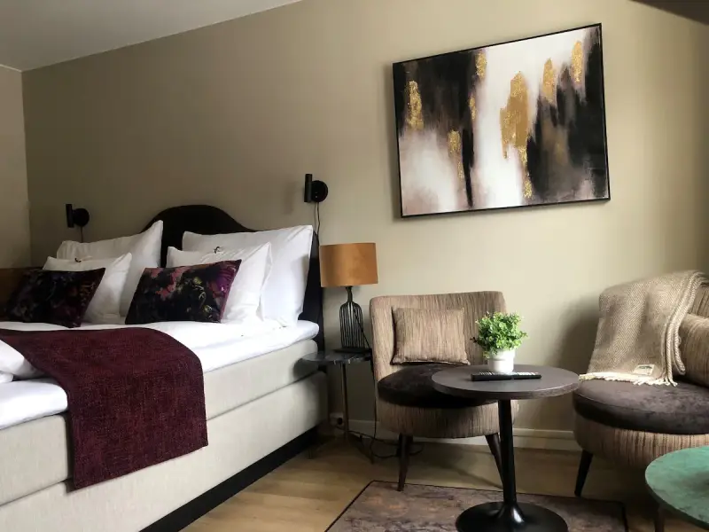 Mysigt hotellrum inredning med stor säng, bekväma fåtöljer och modern konst.
